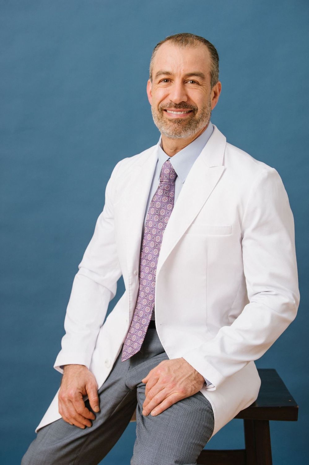 Man in suit, smiling, holding smartphone.