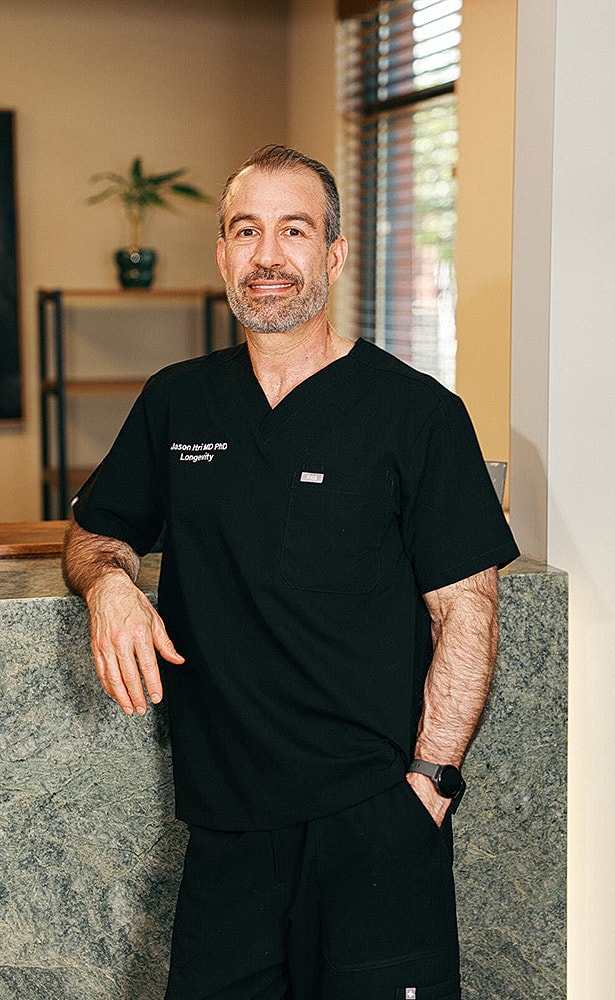 Man in black scrubs standing by a reception desk.